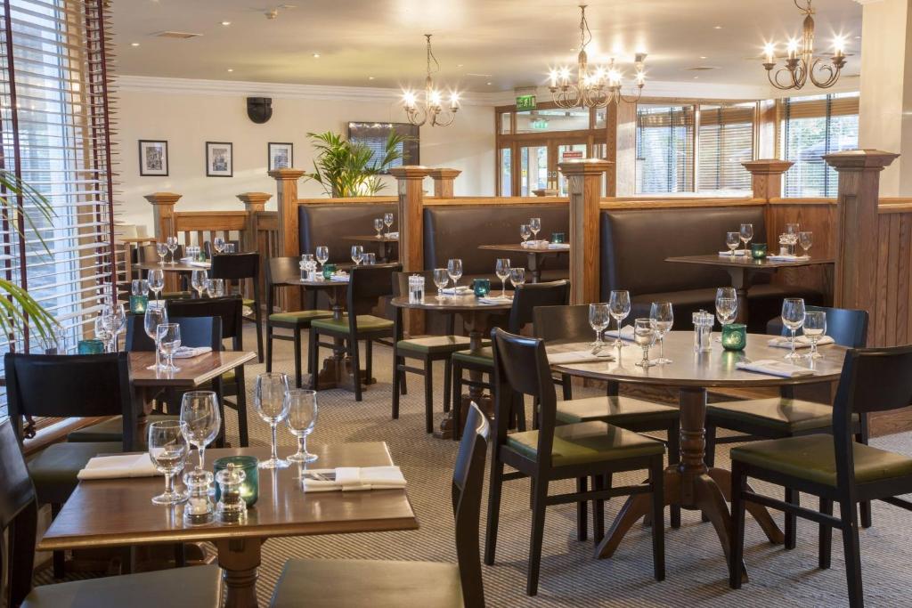 Un restaurante con mesas y sillas de madera y ventanas. en Holiday Inn York by IHG, en York