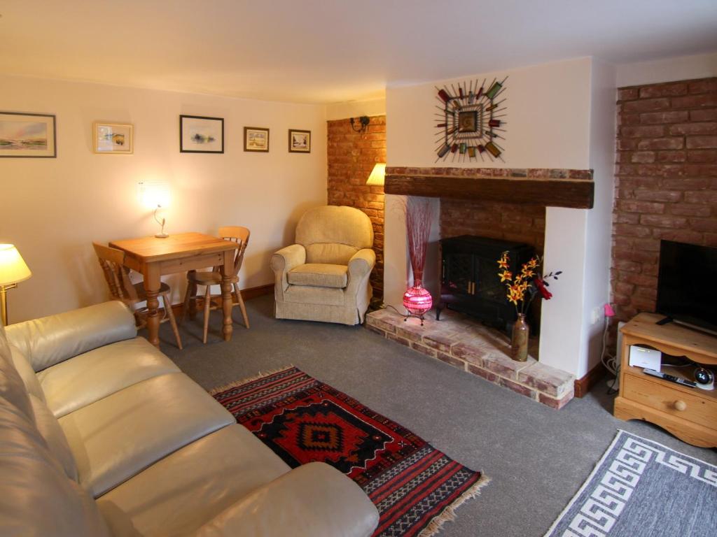 a living room with a couch and a fireplace at Hollyhocks Cottage in Docking