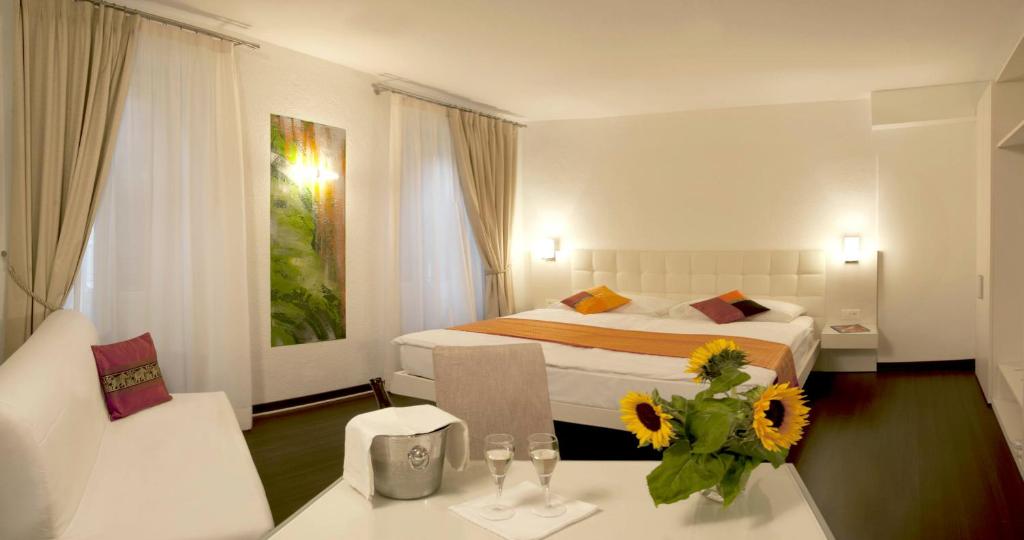 ロカルノにあるHotel Americaのベッドと花がテーブルに飾られたホテルルーム