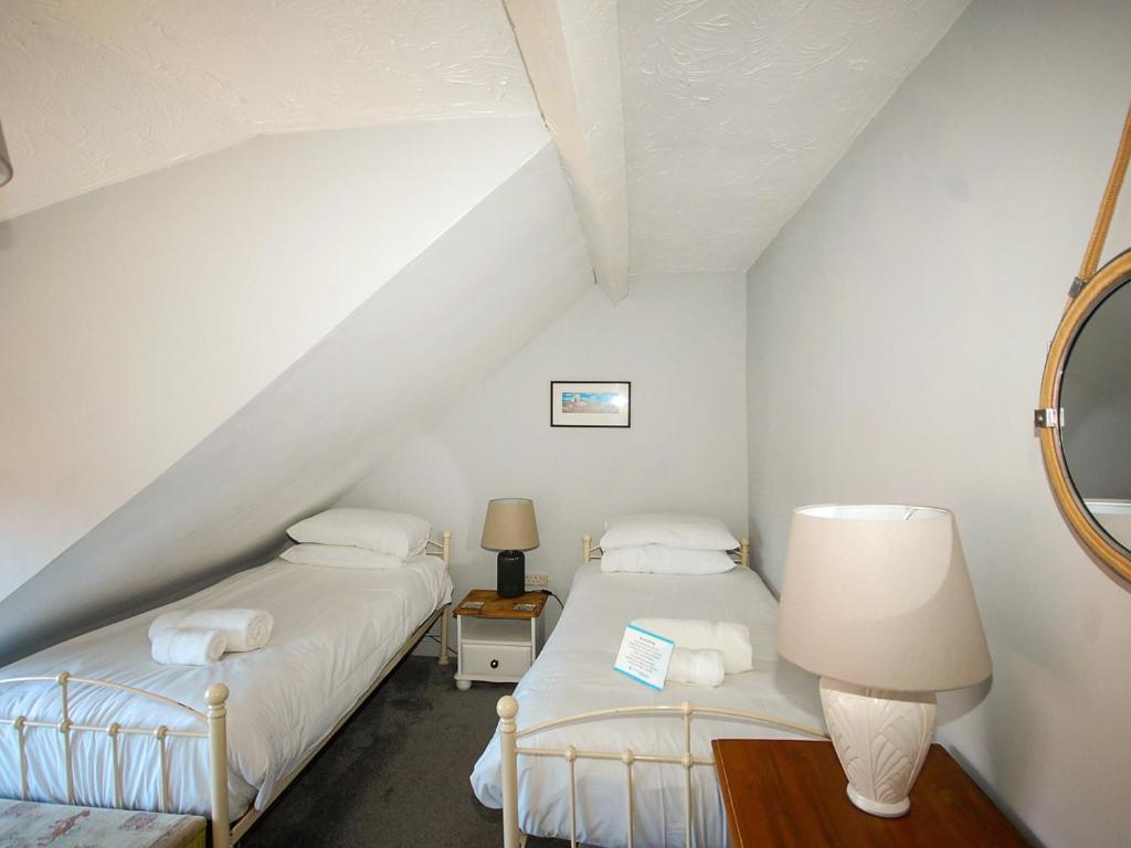 two beds in a attic room with white walls at Wherry Cottage in Wells next the Sea