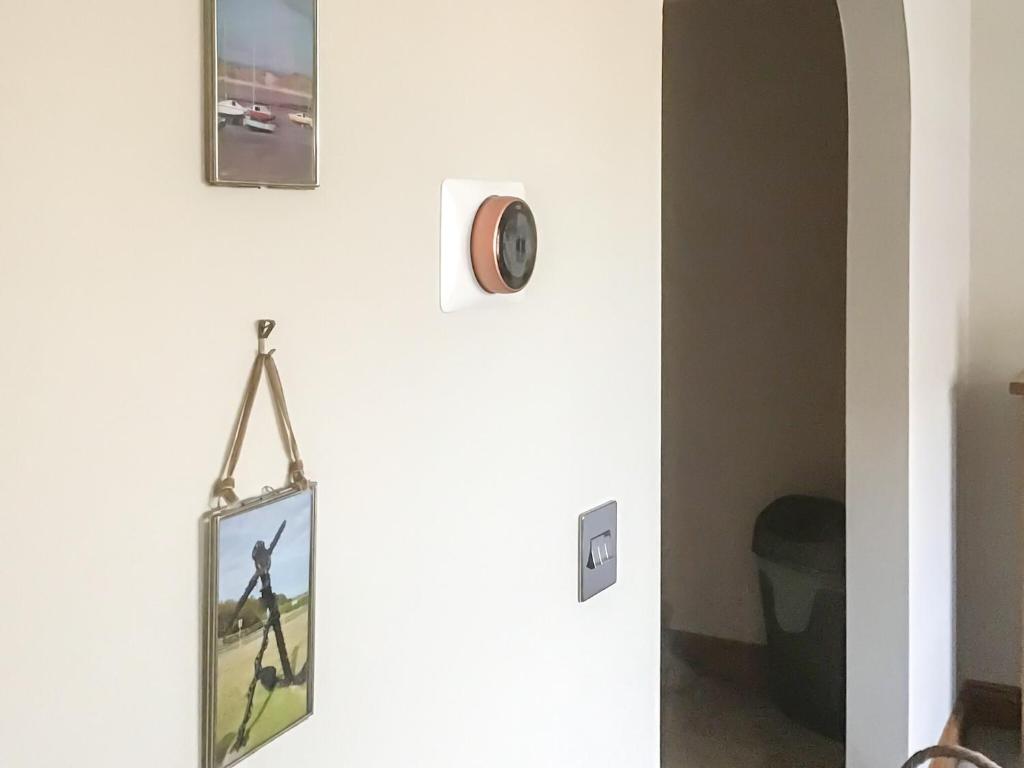 a mirror hanging on a wall with a clock on it at Ebba's Neuk in Beadnell