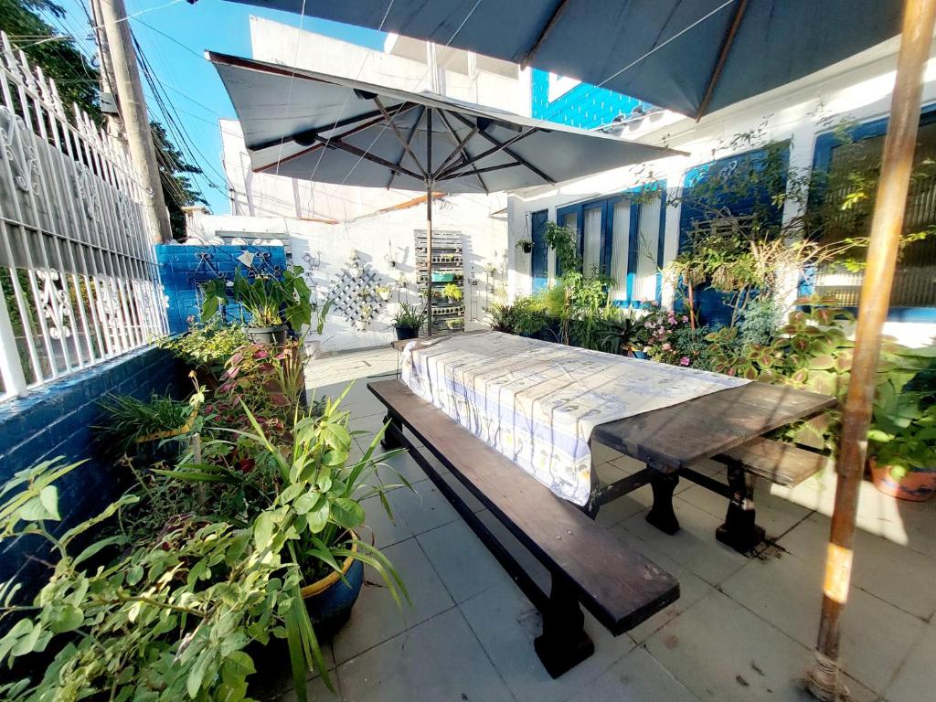 une terrasse avec un banc en bois et un parasol dans l'établissement Casa Espaçosa 6 Qts Churrasqueira 10 min Praia do Forte, à Cabo Frio