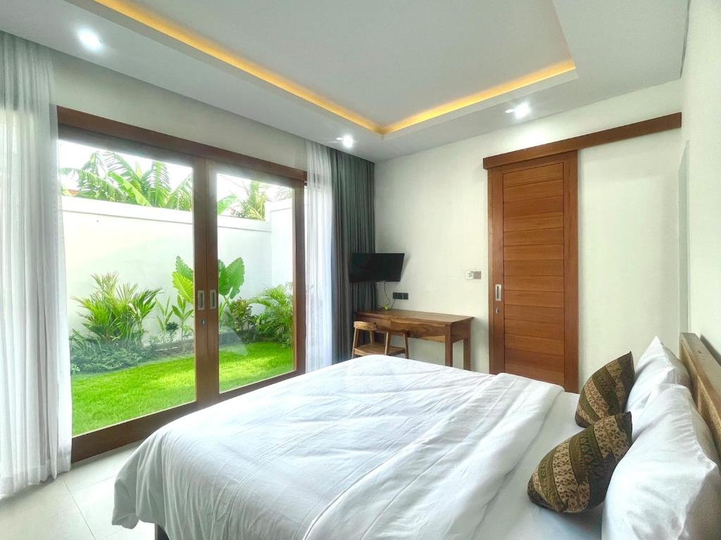 坎古Mahayasa Villa with garden的一间卧室，配有一张大床和一扇大窗户。