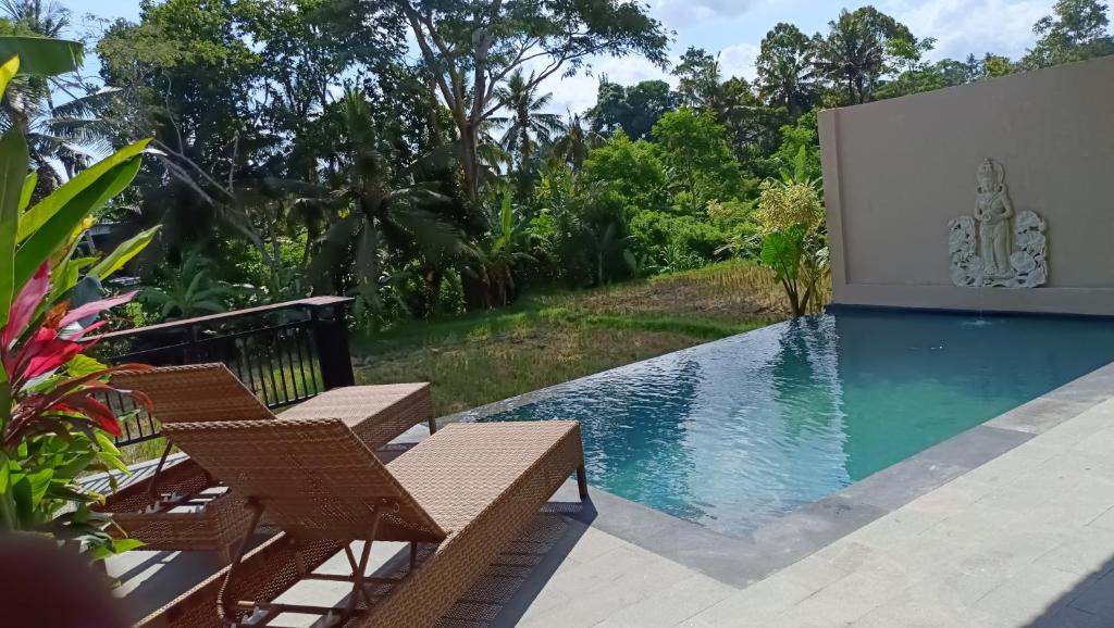 a view of a swimming pool with chairs and trees at Santika villa ubud in Ubud