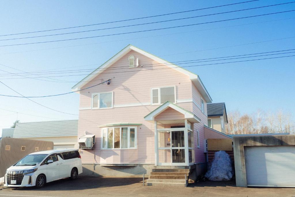 倶知安町にあるNiseko Pink houseのピンクの家の前に駐車した白車