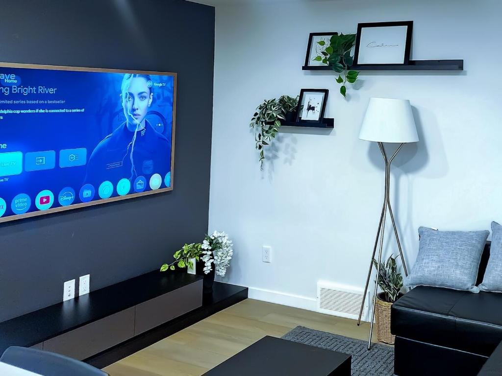 un soggiorno con una TV a schermo piatto su una parete di Cozy 2 BR Suite Self check-in I Free Park Pass a YYC