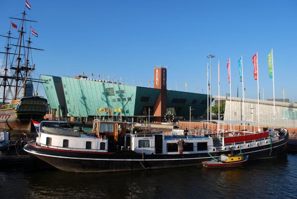 um barco ancorado na água em frente a um edifício em Hotelboot Zwaan em Amesterdão
