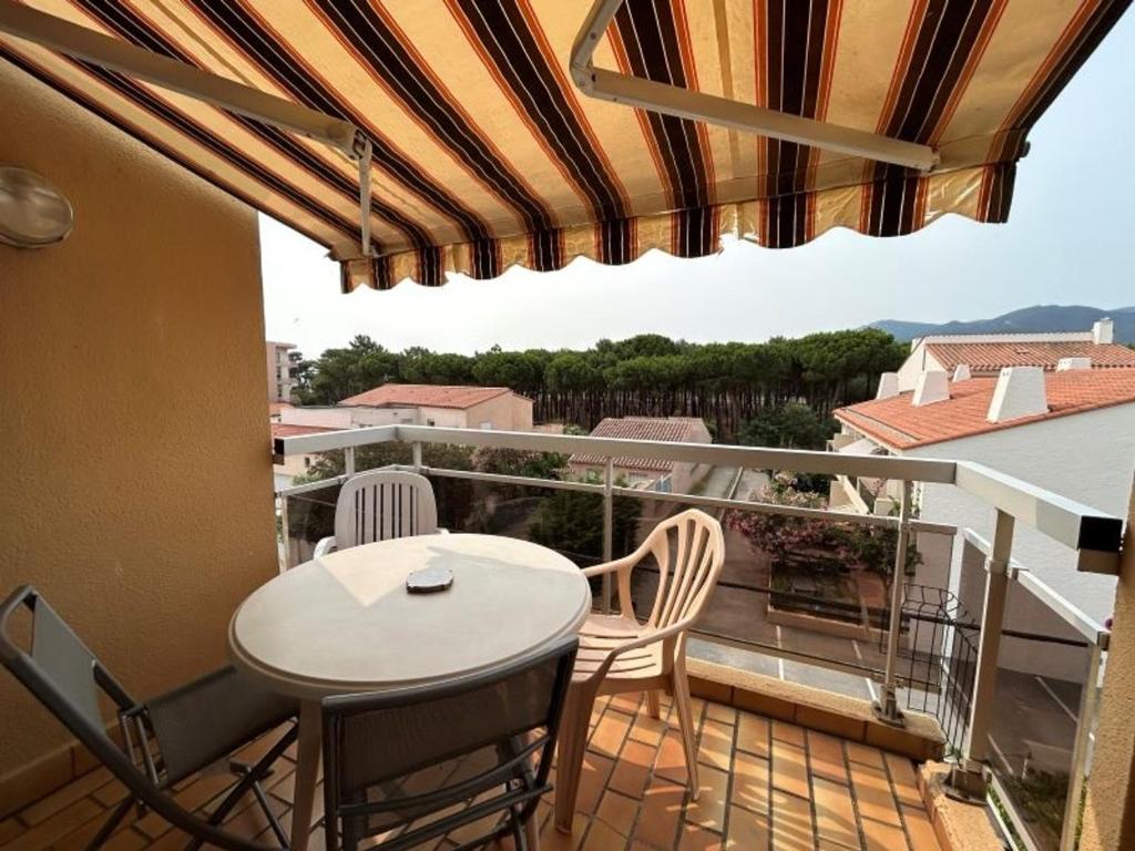 un patio avec une table et des chaises sur un balcon dans l'établissement Appartement mezzanine 4 couchages - FR-1-837-21, à Argelès-sur-Mer
