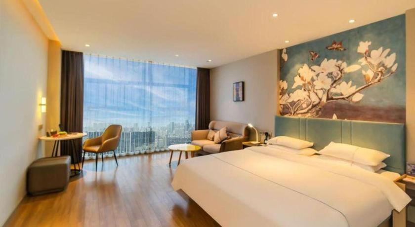 a bedroom with a large bed and a living room at Magnotel Tongxiang Shimao Center in Jiaxing