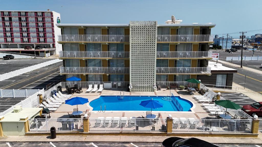 a pool with chairs and umbrellas in front of a building at Landmark Motel in Wildwood
