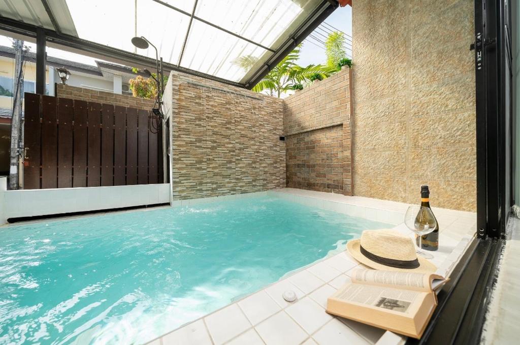 a swimming pool with a hat and a bottle of wine at Laguna Townhouse with private pool and your own gym near Bangtao Beach in Laguna Phuket