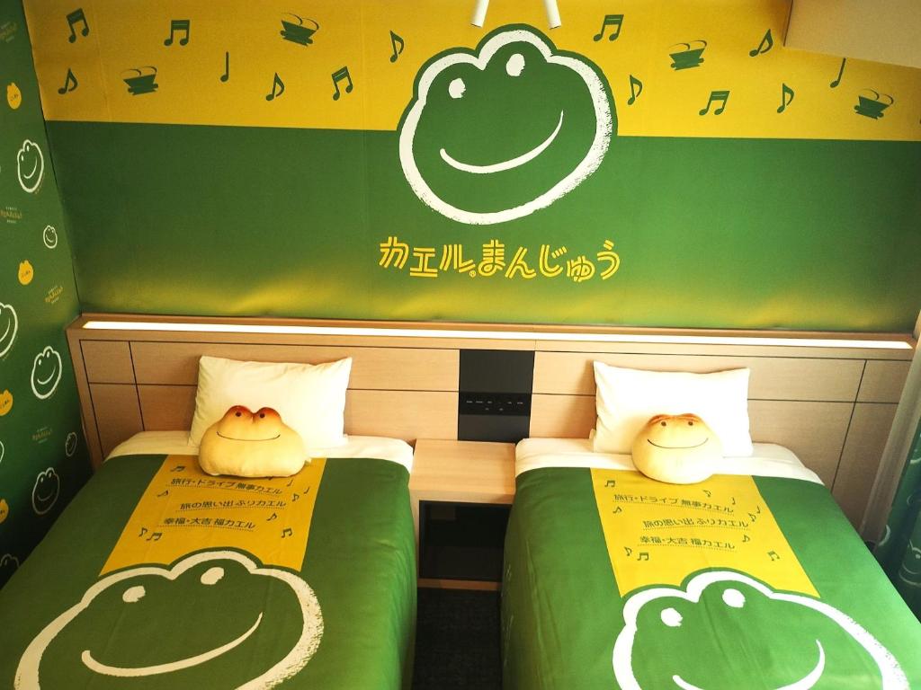 two beds in a room with smiles painted on them at Henn na Hotel Premier Nagoya Fushimiekimae in Nagoya