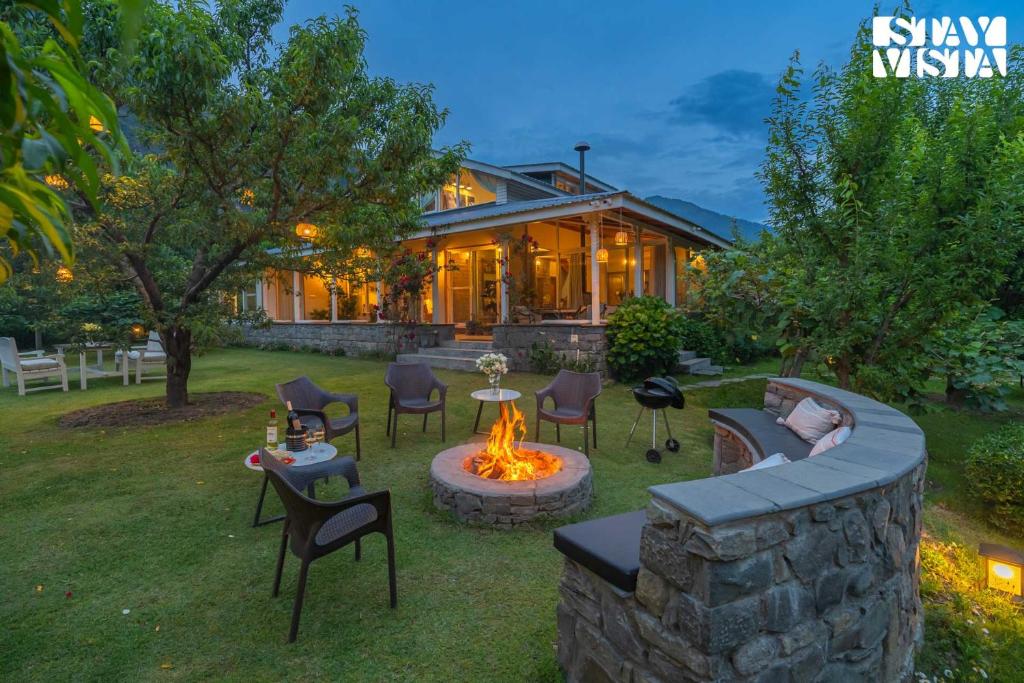 a backyard with a fire pit and a house at StayVista at Mayflower Aramgarh with Orchards, BBQ in Manāli