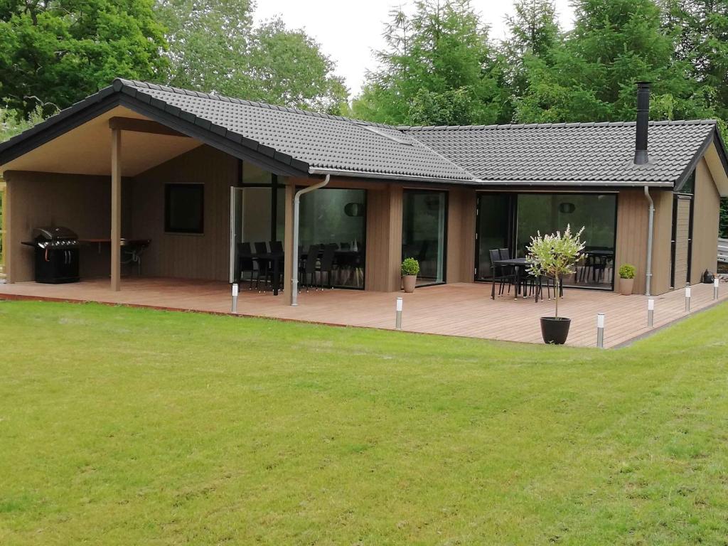 una casa con una gran terraza con mesas y sillas en Charming Cottage In Fjellerup With Indoor Spa, en Glesborg