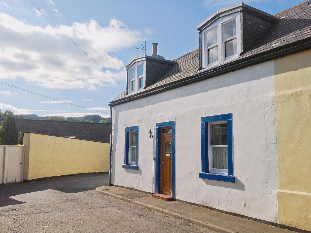 a white house with blue windows and a blue door at Kirsty Cottage in Moffat