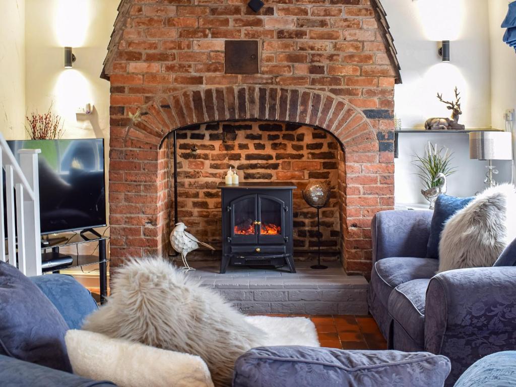 a brick fireplace in a living room with blue couches at Quay Cottage in Bewdley