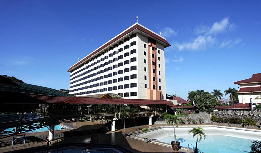 a large white building with a pool in front of it at Horison Ultima Bandung in Bandung
