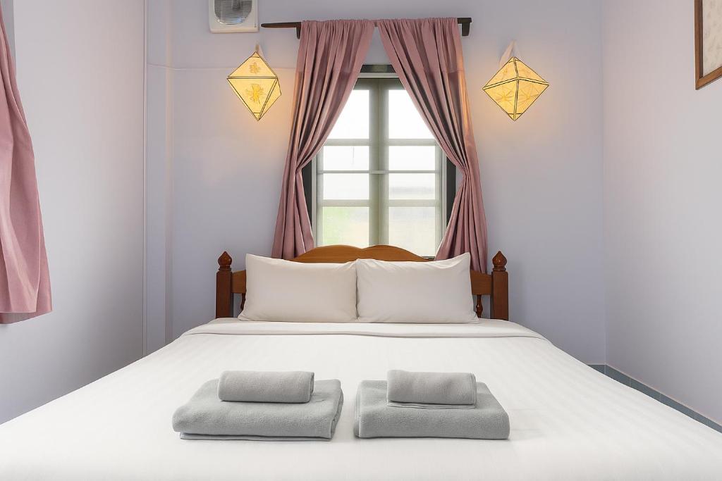 a bed with two pillows in front of a window at PP Guesthouse LPB in Luang Prabang