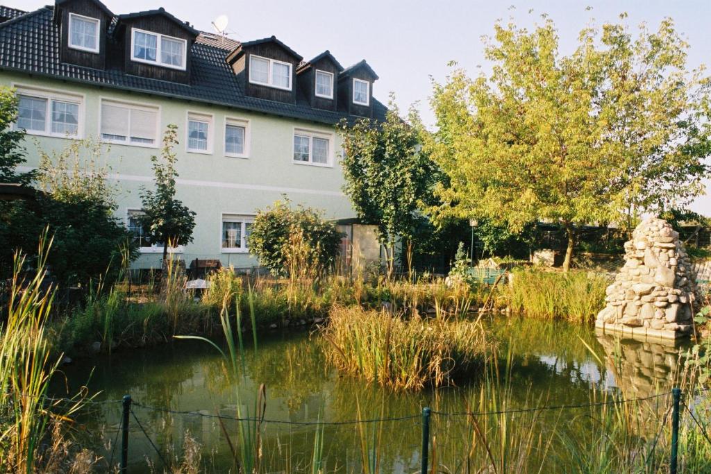 a house and a pond in front of a building at Hotel Gasthof Goldener Hahn in Frankfurt Oder