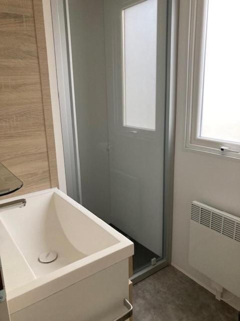 a white bathroom with a tub and a window at Le Domaine des Pins in Saint-Hilaire-de-Riez