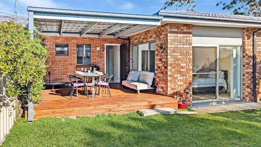 a wooden deck with a table and chairs in a yard at Seashore Villa by Experience Jervis Bay in Vincentia