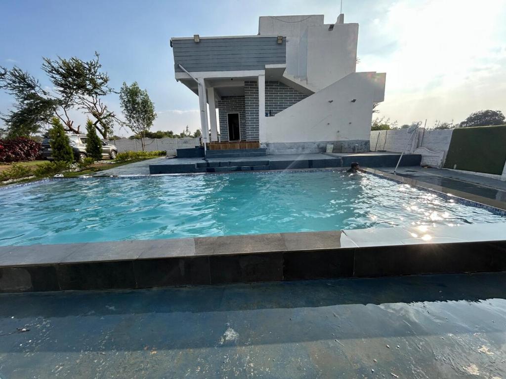 a swimming pool in front of a house at DRZ Farm Stay with Private Pool 2BR by Homeyhuts 