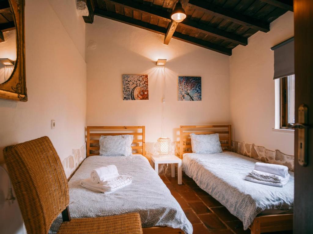 um quarto com 2 camas, uma cadeira e um espelho em Quinta Japonesa em Carvalhal Bemfeito