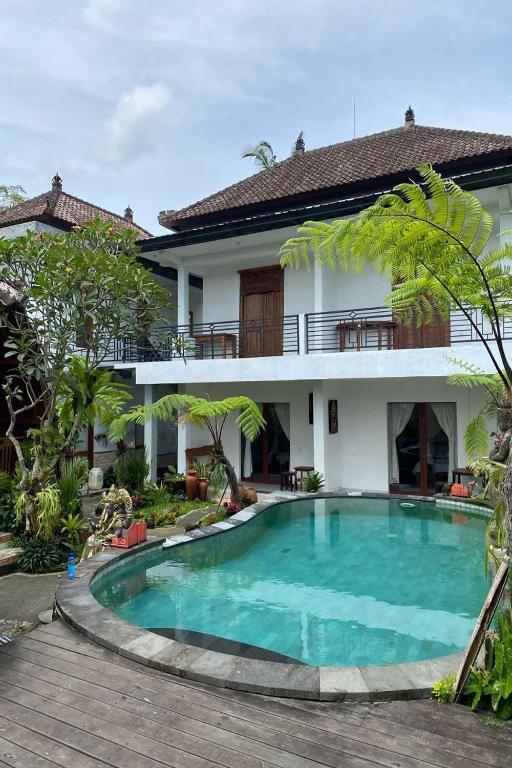 a villa with a swimming pool in front of a house at Budha House Ubud in Ubud
