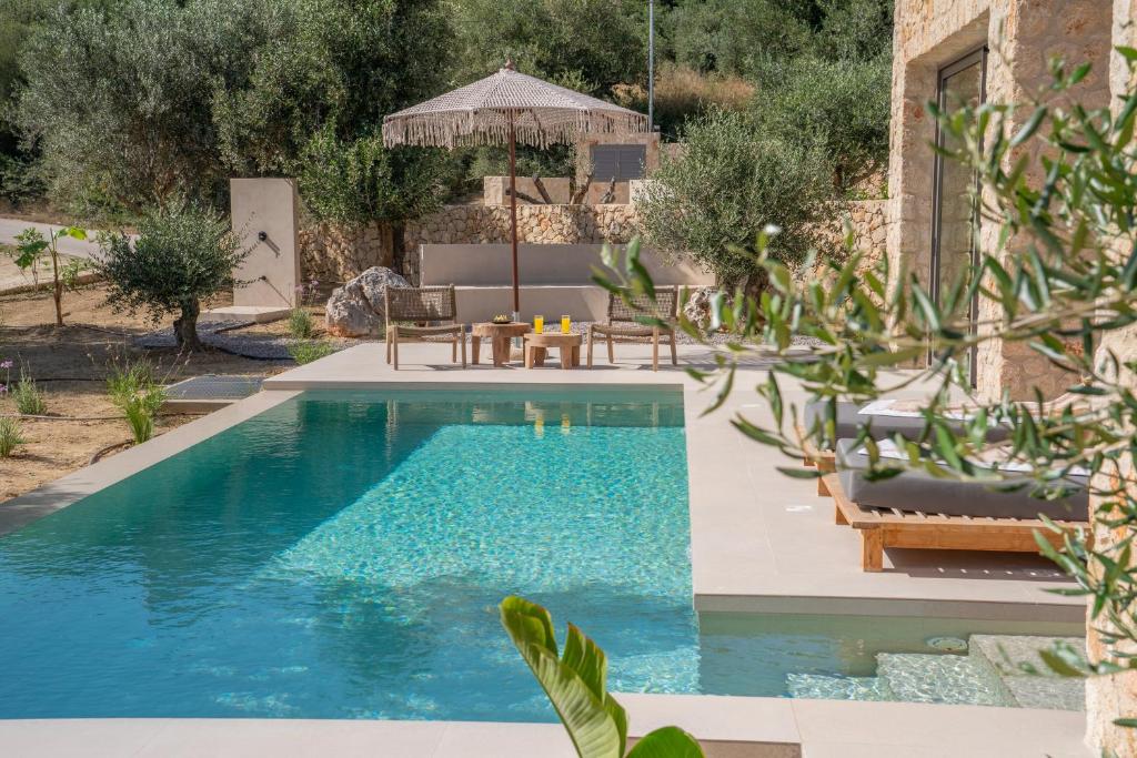 a pool in a backyard with chairs and a table at Lithos Art Villas - Armonia in Lakíthra