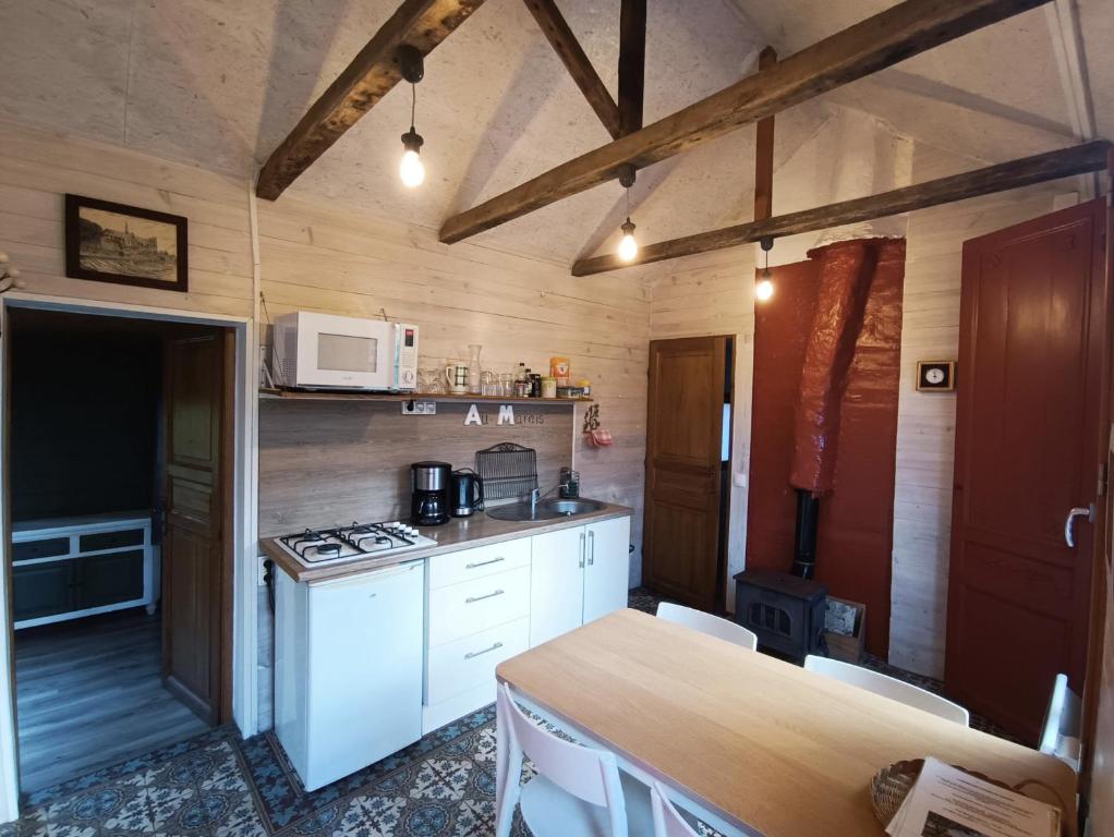 una cucina con mobili bianchi, un tavolo e un microonde di Au Marais ad Amiens