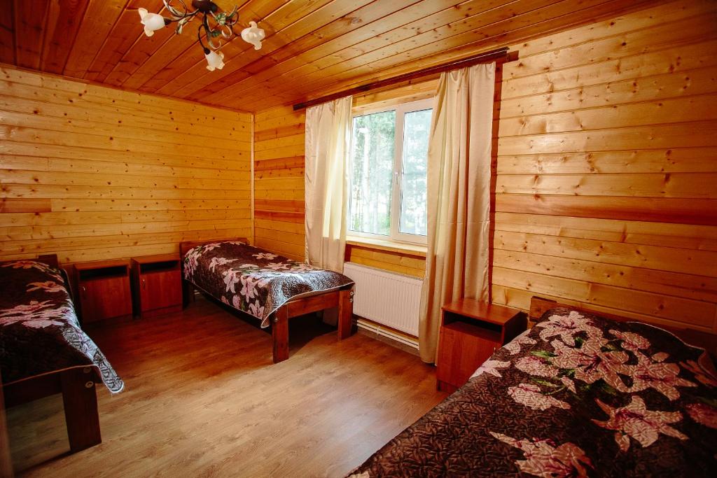 a room with two beds and a window in a log cabin at Baza otdyha Polushkino in Spas-Klepiki