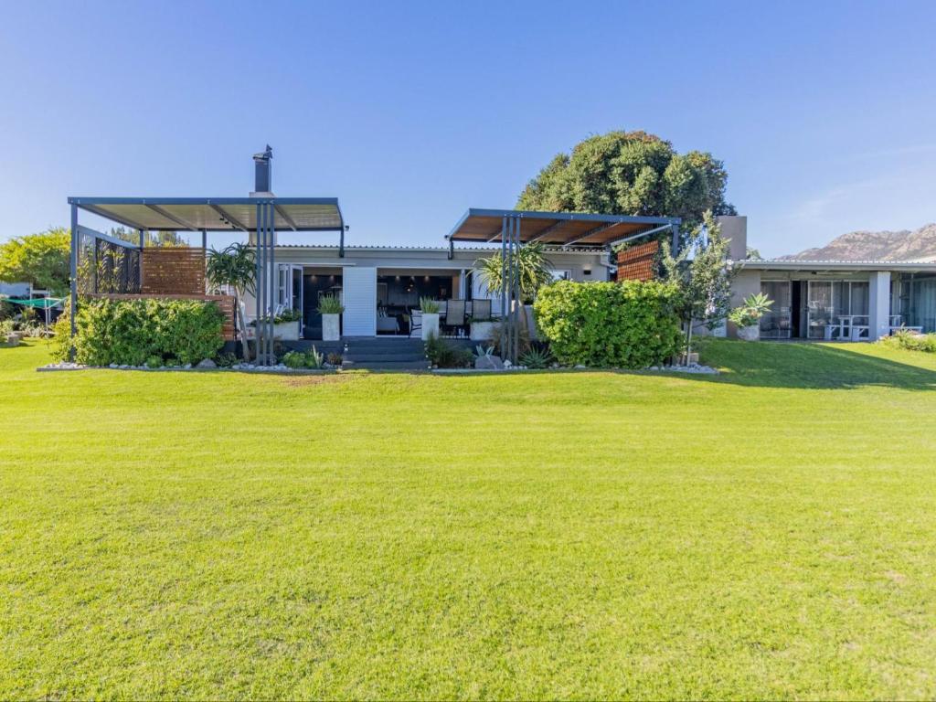 a house with a lawn in front of it at Beachwood Cottage in Gordonʼs Bay