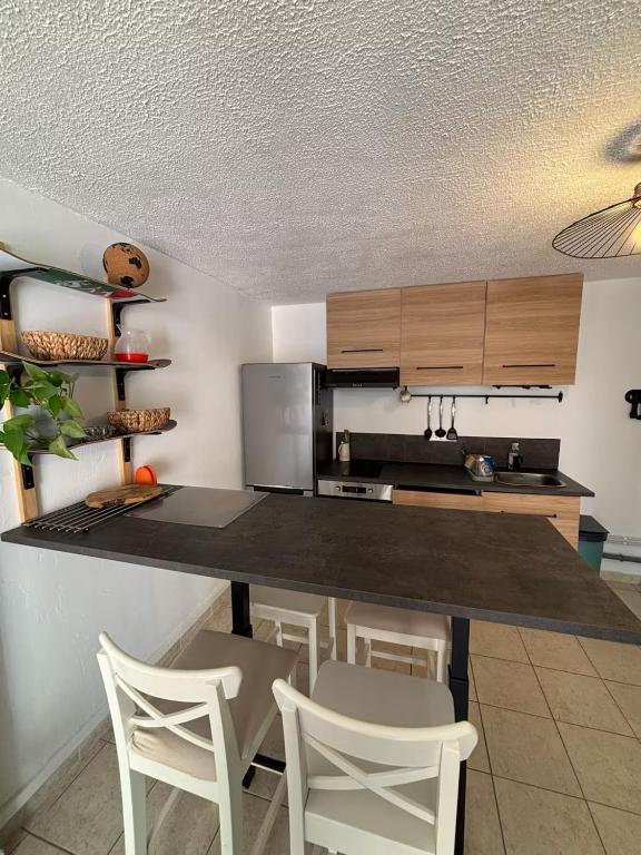 a kitchen with a counter and some chairs in a room at Appart proche du lac et plages in Soustons