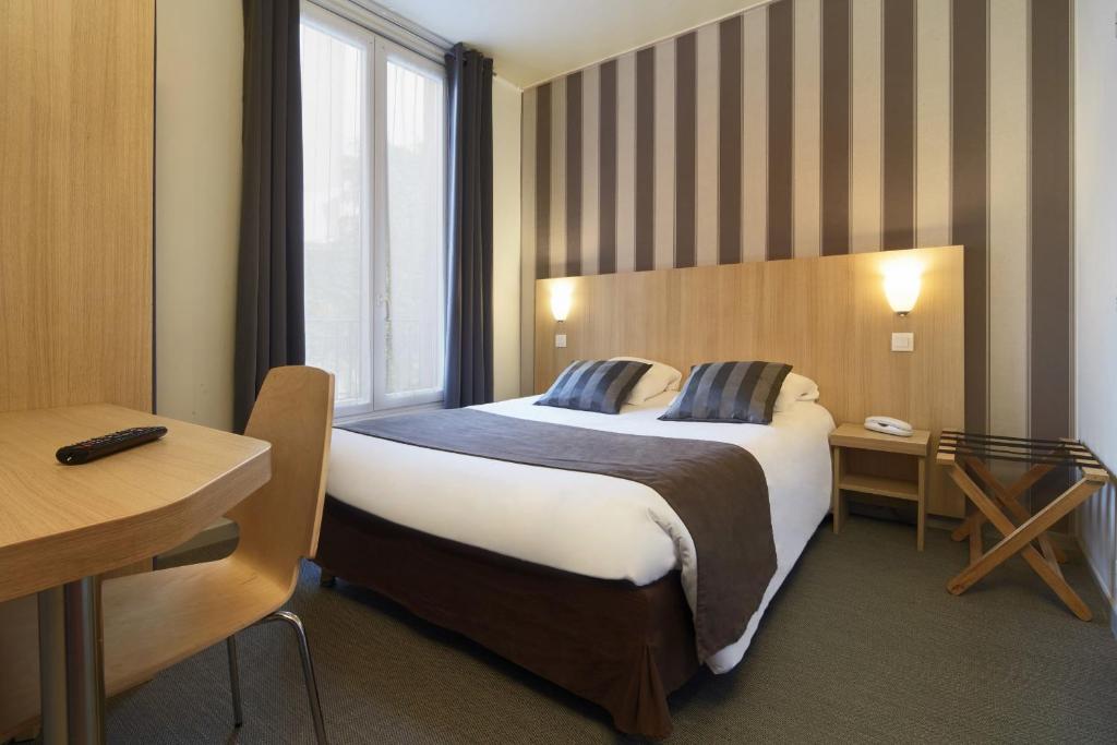 um quarto de hotel com uma cama grande e uma janela em Hotel Paris Villette em Paris