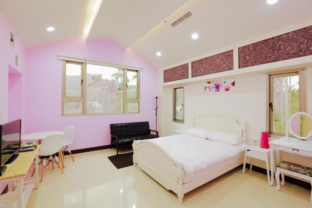 1 dormitorio con paredes rosas, 1 cama y escritorio en Love B&B, en Sanyi