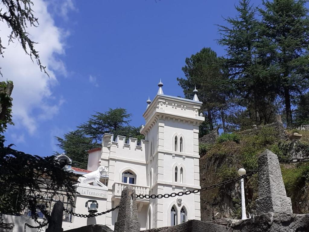 un bâtiment blanc avec une tour sur une colline dans l'établissement Chambre d'hôtes Napoléon à La Terrasse piscine local vélo, à Tournon-sur-Rhône