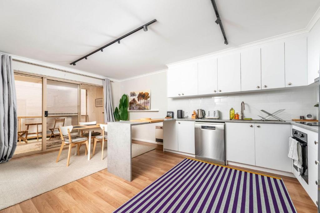 a kitchen with white cabinets and a table with chairs at Stylish 2BR Apartment in Kingston Close to Lake in Kingston 