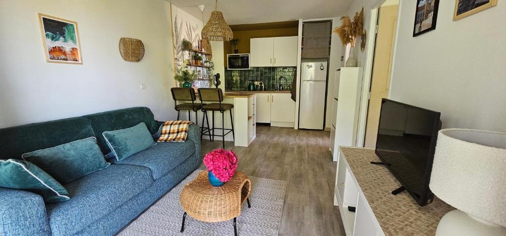 ein Wohnzimmer mit einer blauen Couch und einer Küche in der Unterkunft Pause Luzienne à deux pas de la plage in Saint-Jean-de-Luz