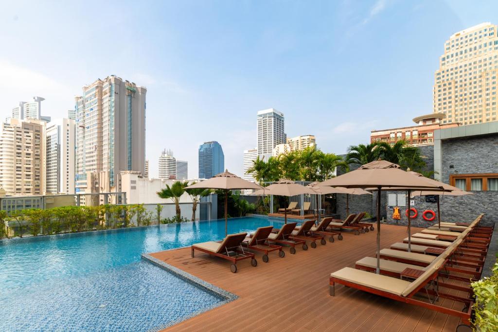バンコクにあるRadisson Blu Plaza Bangkokのラウンジチェアとパラソル付きのスイミングプール