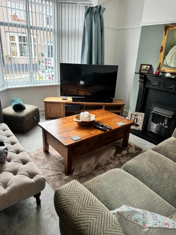a living room with a television and a coffee table at Beautiful three bedroom house in Liverpool