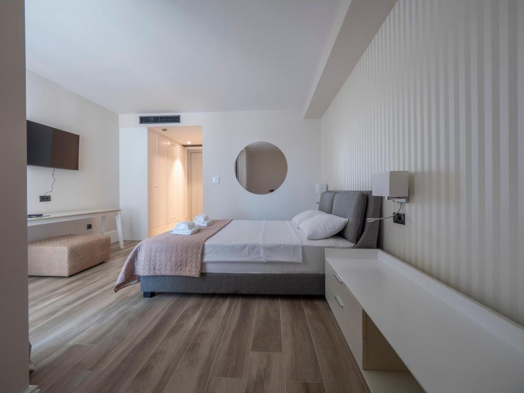 a white bedroom with a bed and a mirror at CASA AL MARE RESIDENCE in Bečići