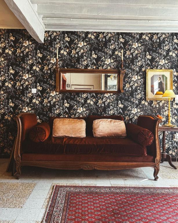 un canapé marron assis dans une pièce avec un miroir dans l'établissement Darlings Guest House, à Saint-Sauveur-en-Puisaye