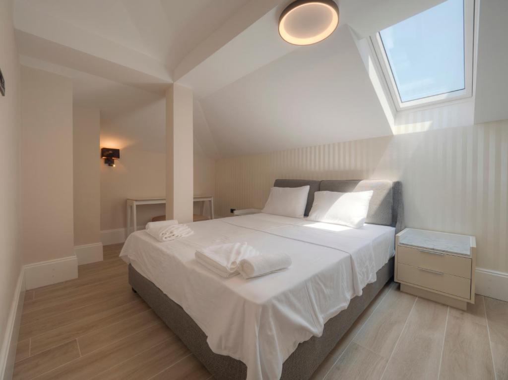 a bedroom with a bed with white sheets and a window at CASA AL MARE RESIDENCE in Bečići