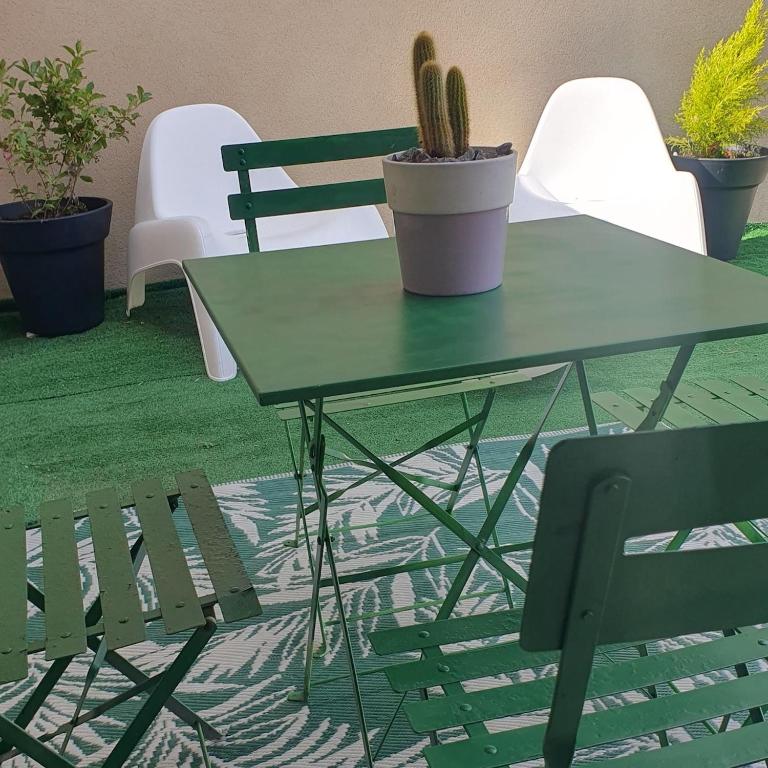 une table verte et une chaise et un cactus dans l'établissement Charmante petite maison proche de la gare, à Terrasson