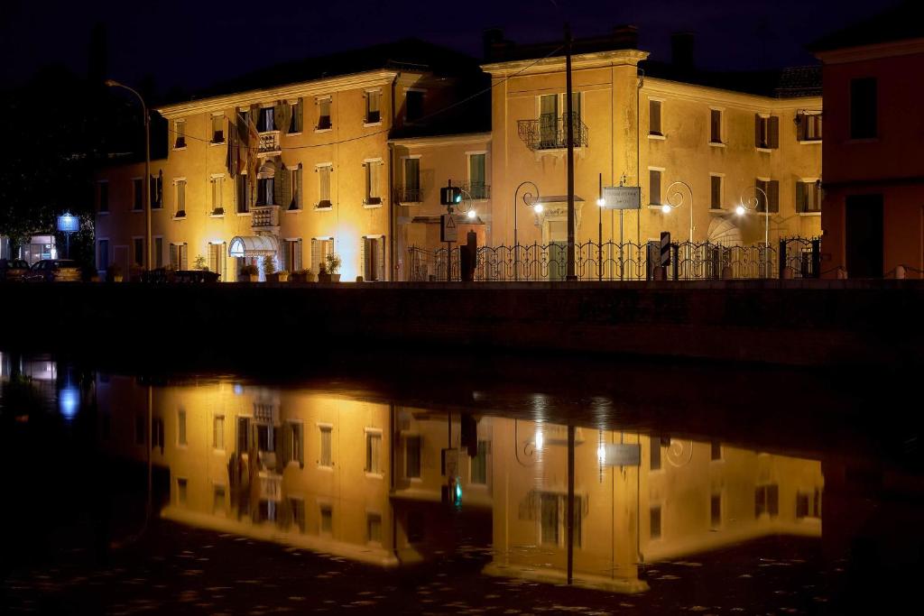 a building with its reflection in the water at night at Hotel Riviera dei Dogi in Mira