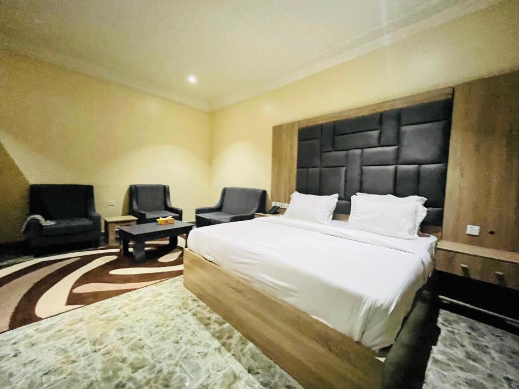 a hotel room with a bed and two chairs at Global Suites in Kano