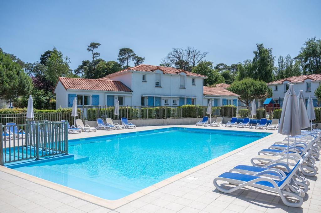 a swimming pool with chairs and umbrellas at Résidence Odalys Le Domaine de l'Océan in Saint-Brévin-lʼOcéan