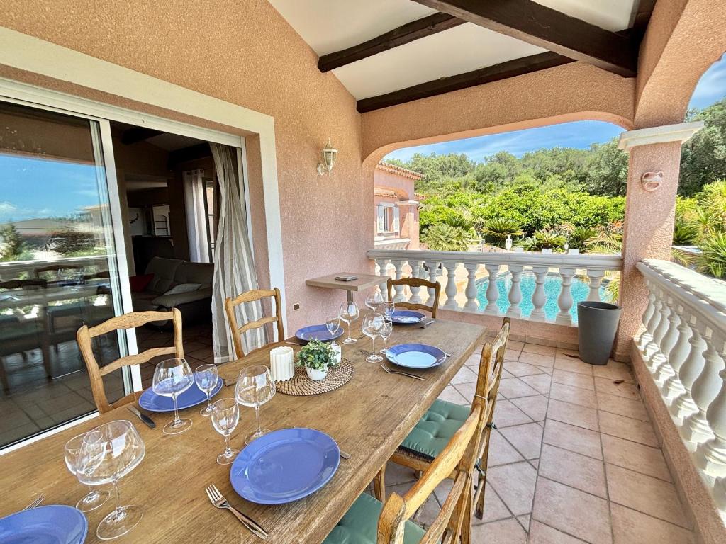 une table sur un balcon avec des assiettes bleues et des verres à vin dans l'établissement Maison avec piscine chemin d'erbajolo proche centre Ajaccio, à Ajaccio