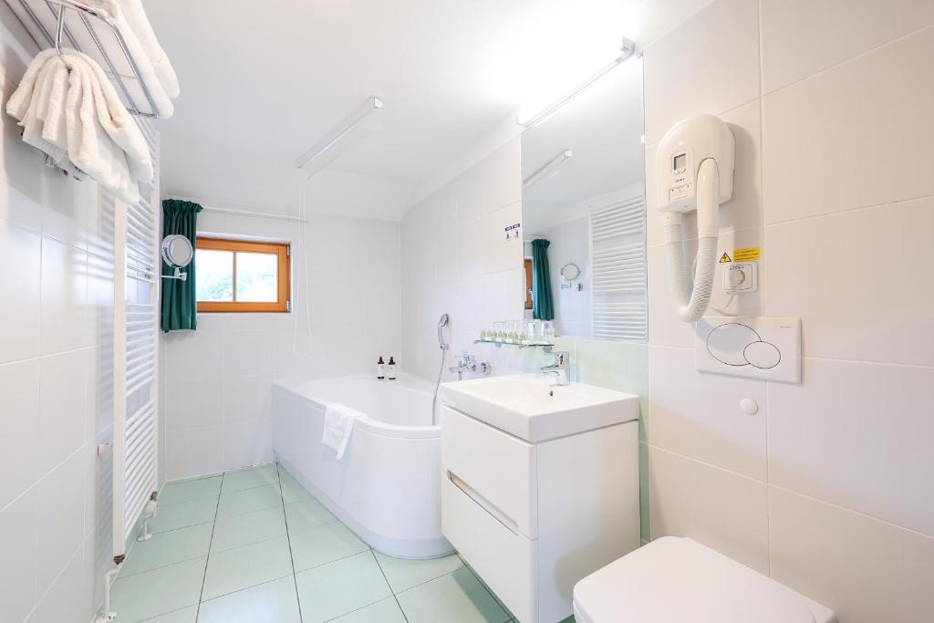 a white bathroom with a tub and a toilet and a sink at Hotel Mlýn in Český Krumlov