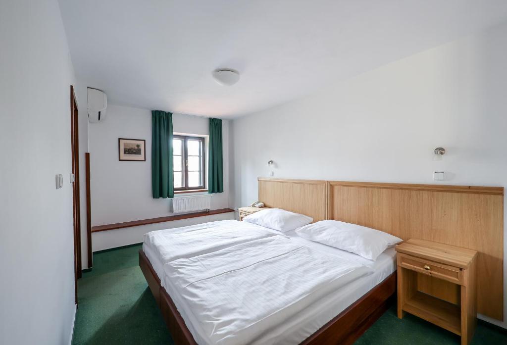 a bedroom with a large bed with white sheets at Hotel Mlýn in Český Krumlov